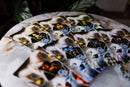 A fan arrangement of illustrated Ignisynthia wild cards featuring stylized faces and abstract artwork, photographed on a round stone surface with a blurred dark background.